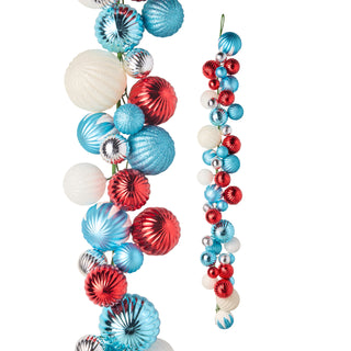 Red, white, and blue Christmas ornament garland with shiny metallic and textured baubles on a white background.
