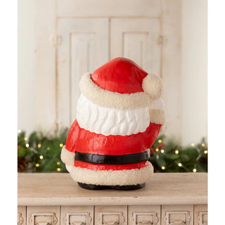 Decorative Santa Claus figure on a mantelpiece with a festive background